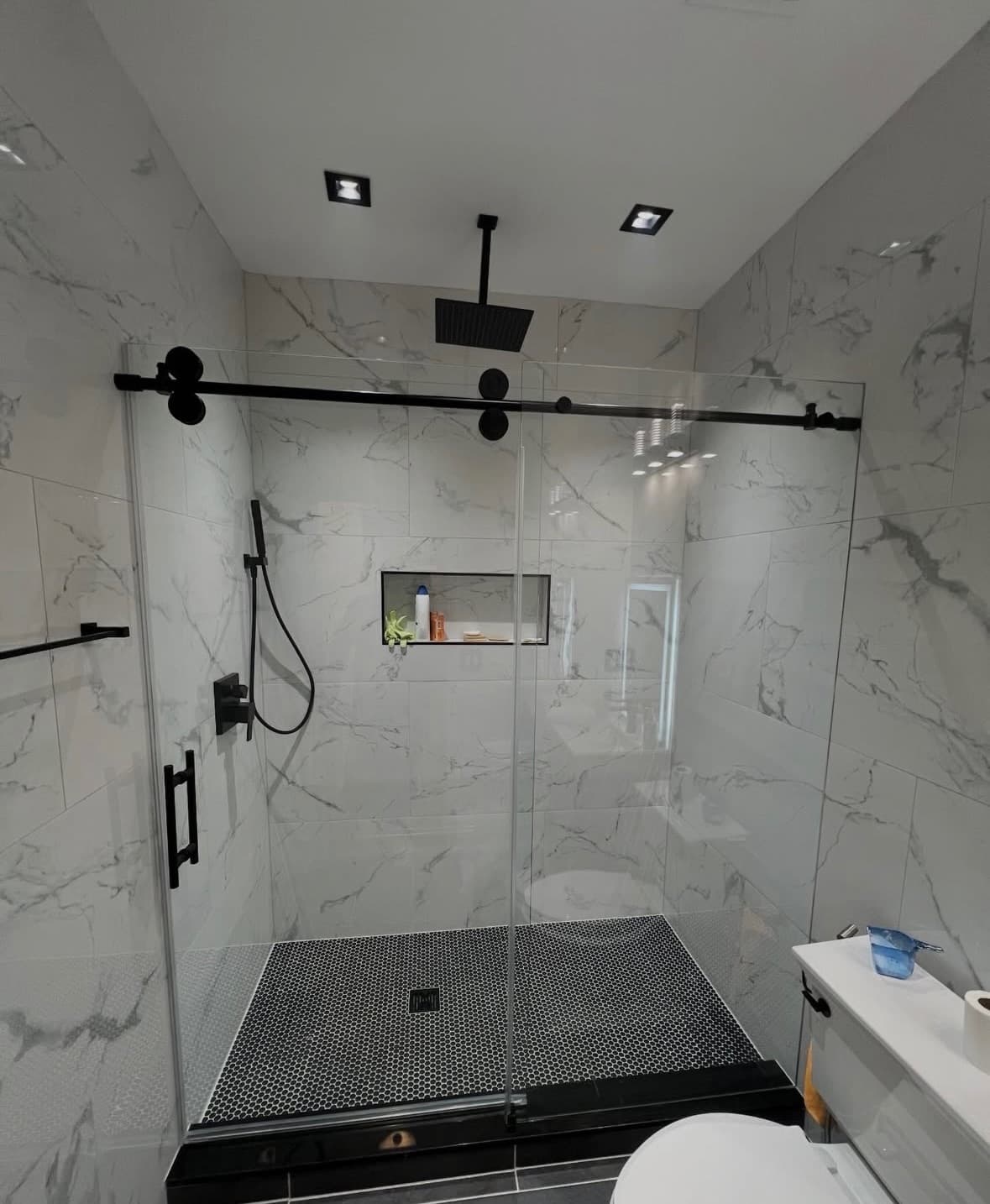 Dramatic powder room with dark walls, fluted wood floating vanity, LVP flooring, and arched LED mirror in Charlotte NC